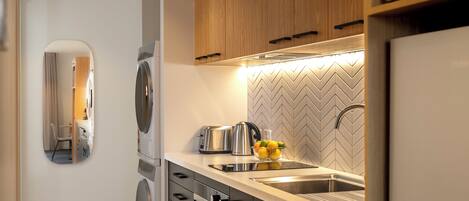 A modern kitchen with a built-in oven, a toaster, a kettle, and a sink.