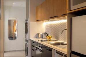 Una cocina moderna con horno integrado, tostadora, hervidor y lavamanos.