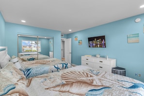A bedroom with two beds, a dresser, a mirror, and a cityscape painting on the wall. - Sombrero Beach Getaway - Pool (Marathon)