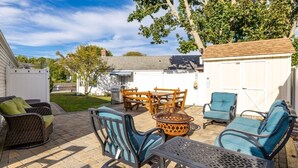 A patio with outdoor furniture, a fire pit, and a shed in a residential setting. - Gorgeous 3-bedroom house in tranquil Westbrook perfect for relaxing getaway (Westbrook)