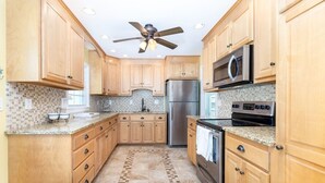 A kitchen with wooden cabinets, a stainless steel refrigerator, a microwave, and an oven. - Gorgeous 3-bedroom house in tranquil Westbrook perfect for relaxing getaway (Westbrook)