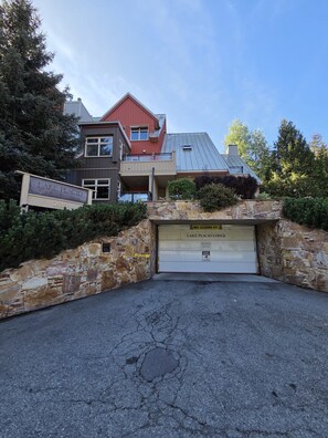 A multi-story building with a garage entrance, stone walls, and a clear sky. - Ultimate Creekside Ski Base • Pool, Hot Tub, Sauna (Whistler)