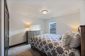 Quarto com cama, cômoda e janela.