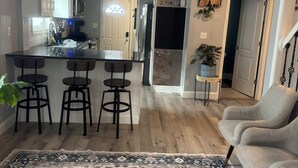 Una cocina moderna con una isla central, taburetes de bar y una lámpara colgante.