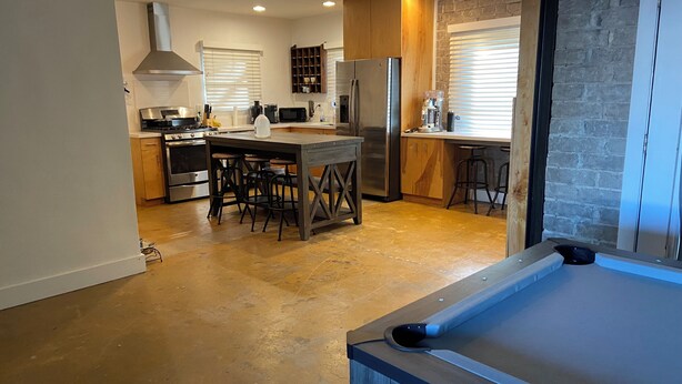 Een moderne keuken met een centraal eiland, barstoelen en een roestvrijstalen koelkast.