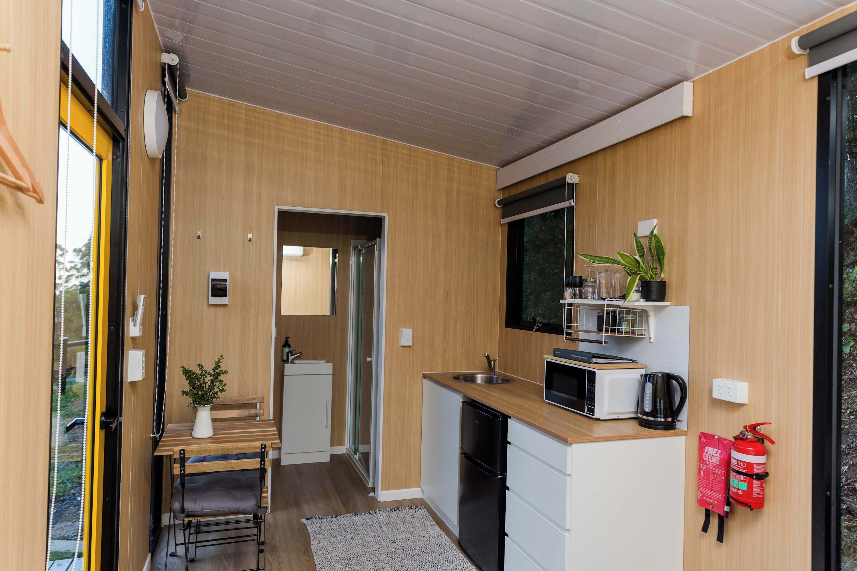 Een kleine keuken met een magnetron, spoelbak en brandblusser.
