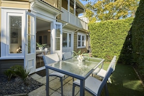 A glass-top table with chairs, a potted plant, and a view of a house with a balcony. - A Real Ponsonby Treat — Two Bedrooms, Parking (Auckland)
