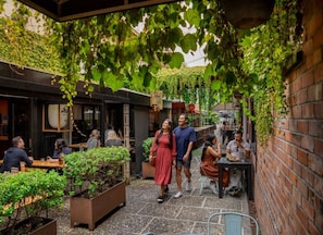 An outdoor café with tables and chairs, surrounded by greenery and brick walls. - A Real Ponsonby Treat — Two Bedrooms, Parking (Auckland)