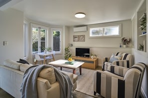 A modern living room with a sofa, striped armchairs, a coffee table, and a flat-screen TV. - A Real Ponsonby Treat — Two Bedrooms, Parking (Auckland)