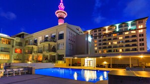 A hotel with a swimming pool, a view of a tower, and multiple balconies. - Sky-High City Retreat Level 12 Studio Apartment (Auckland)
