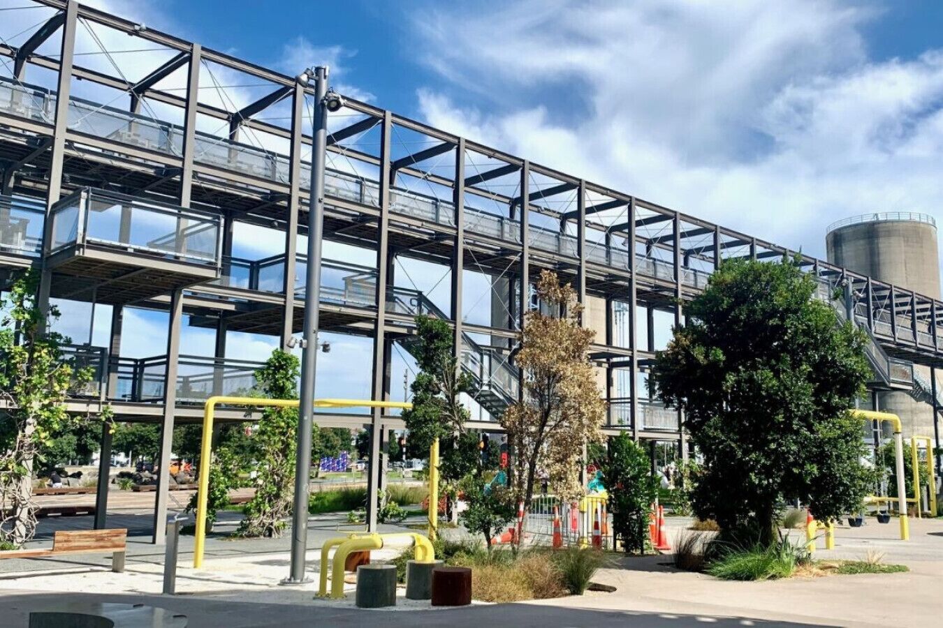 Un edificio moderno con fachada de vidrio, estructura metálica y equipamiento de ejercicios al aire libre.