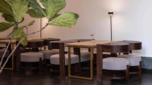 A modern dining area with round tables and cushioned chairs, a potted plant, and a floor lamp. - Dali Sky & Erhai Sea View Holiday Inn (Dali)
