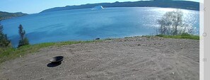 A dirt path leading to a body of water with a clear view of the lake and distant mountains. - Cozy Beachfront Cottage Retreat w/ Loft Workspace, Stunning Views & Beach Access (King's Point)