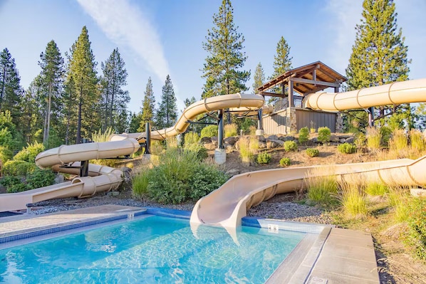 A pool area with multiple slides and a wooden deck structure.