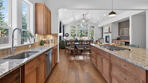 A modern kitchen with granite countertops, wooden cabinets, and a central island. - Downey Pines: Luxury 5bd Mountain Retreat ~ Close to Bachelor & Sunriver (Bend)