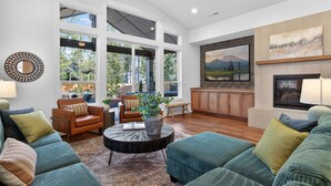 A spacious living room with a large window, a fireplace, and a kitchen area. - Downey Pines: Luxury 5bd Mountain Retreat ~ Close to Bachelor & Sunriver (Bend)