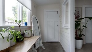 Kapea käytävä, jossa on puinen penkki, valkoiset ovet ja ruukkukasveja.