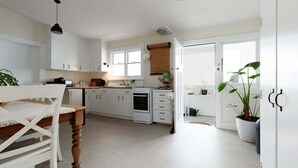 Keittiössä on valkoiset kaapit, puinen ruokapöytä ja ruukussa oleva kasvi.