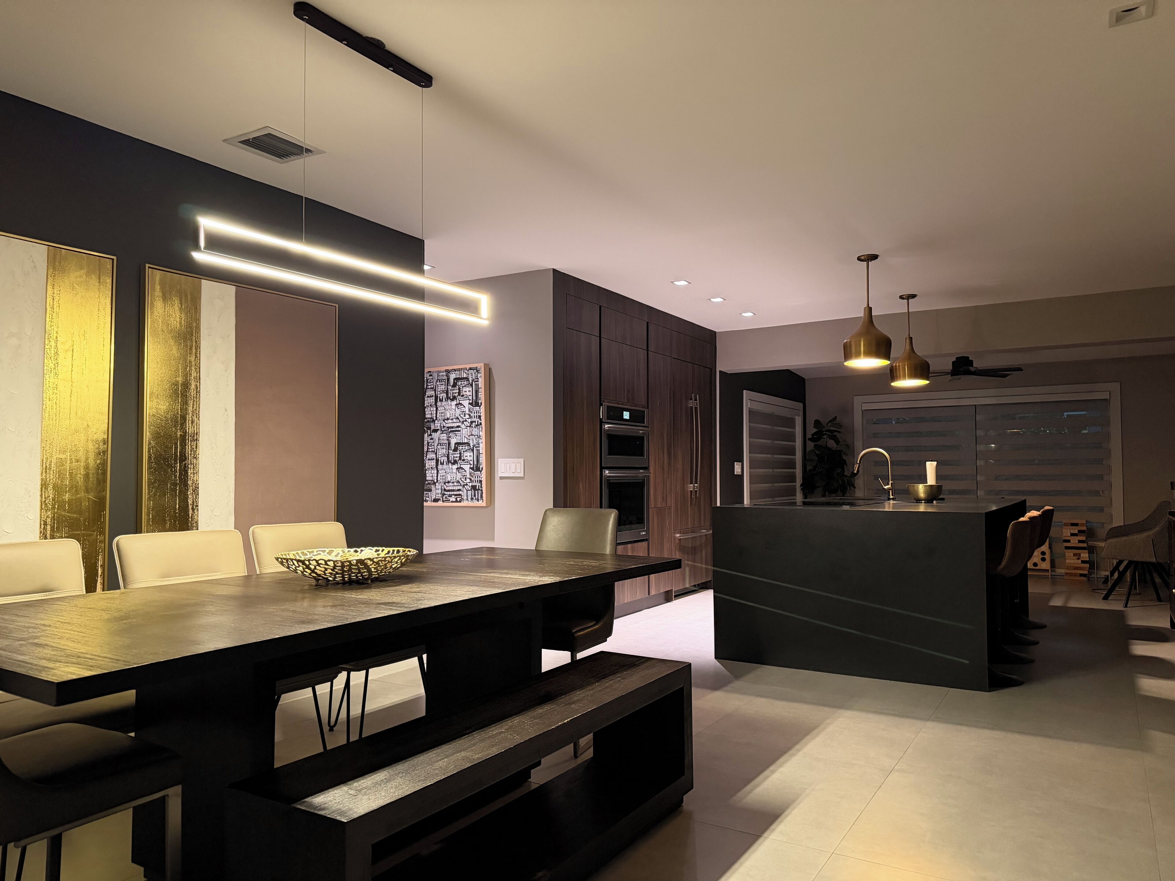 Una cocina moderna con armarios oscuros, una isla central e iluminación colgante.