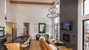 Una cocina moderna con una isla central, una zona de comedor con un sofá y sillas, y una chimenea.