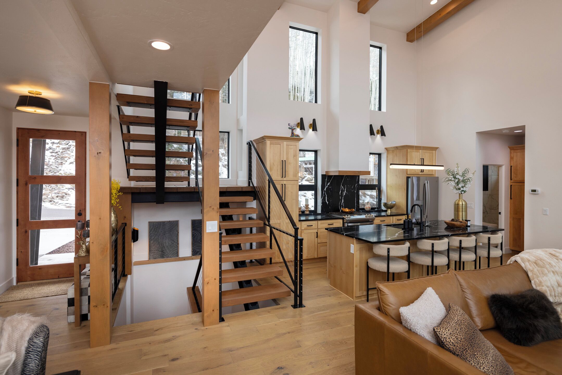 A spacious living area with a wooden staircase, a kitchen with modern appliances, and a cozy seating area.