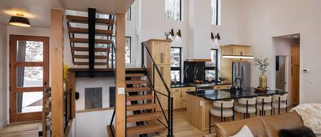 A spacious living area with a wooden staircase, a kitchen with modern appliances, and a cozy seating area.