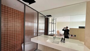 A modern bathroom with a large mirror, a glass shower enclosure, and a sink with toiletries. - Calmstay-Soluna Pearl Villa-Ocean Park (Nghia Tru)