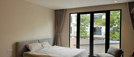 A bedroom with a bed, a chair, and a view of the outside.