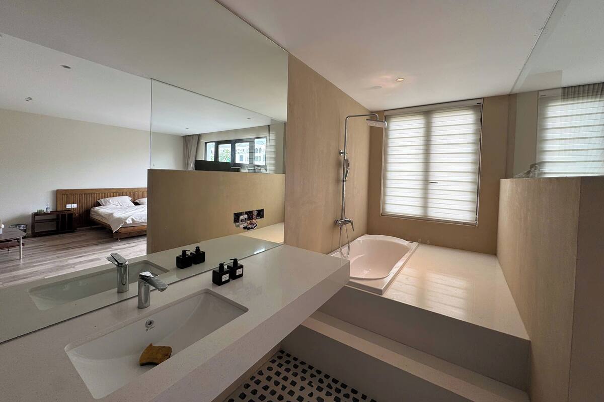 Une salle de bain d’hôtel moderne, dotée d’un grand lavabo, d’une baignoire et d’une douche.