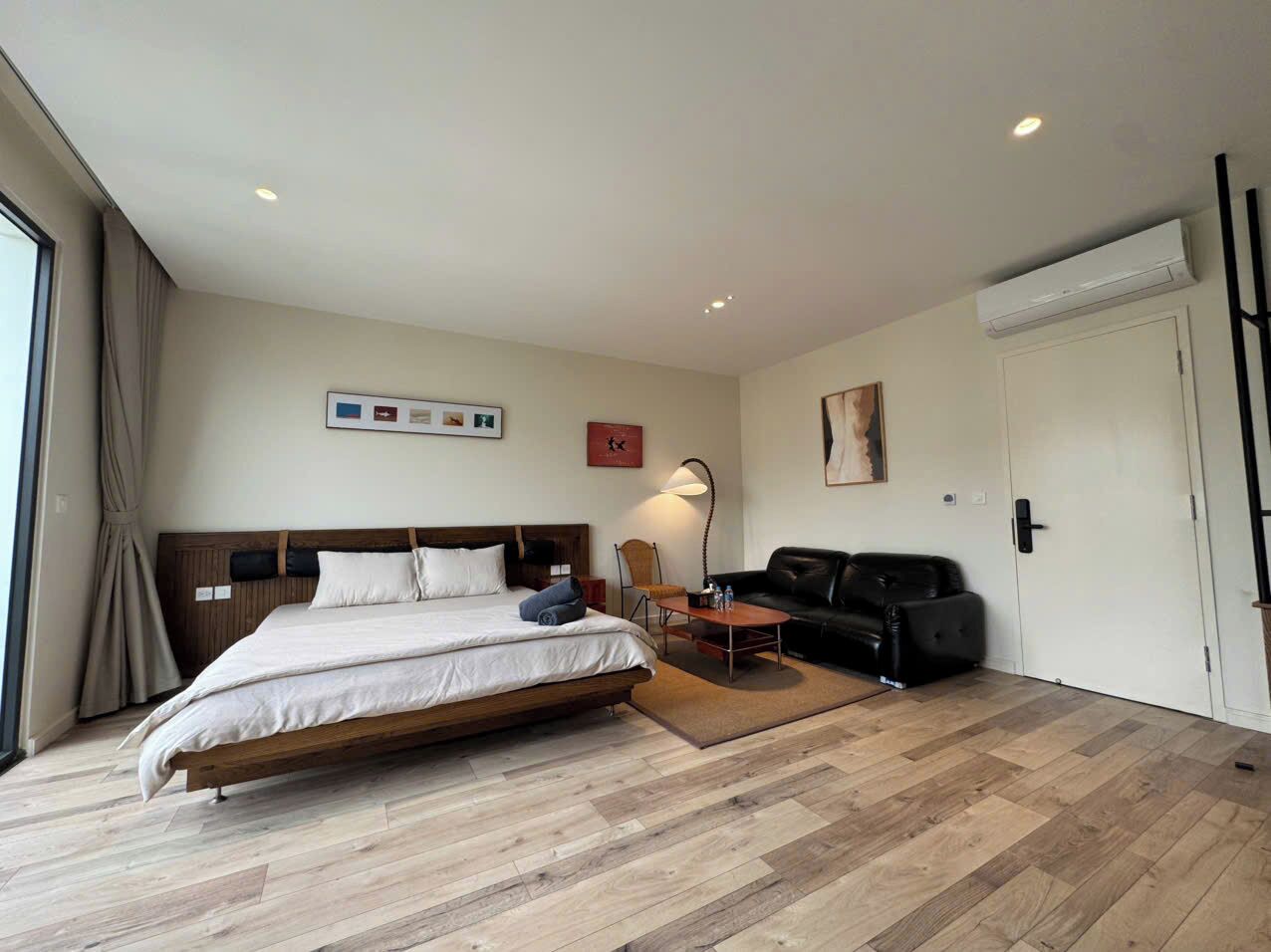 A hotel room with a large bed, a sofa, a desk, and a chair.
