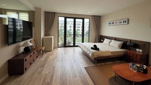 A hotel room with a bed, a TV, a desk, a chair, and a balcony with a view of buildings. - Calmstay-Soluna Pearl Villa-Ocean Park (Nghia Tru)