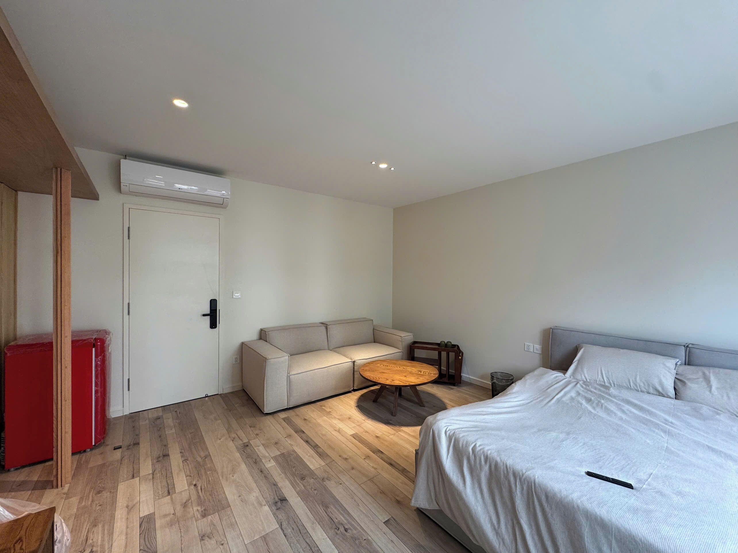 Et moderne soveværelse med seng, sofa, et lille rundt bord og en aircondition-enhed på væggen.