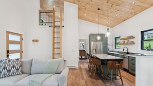 Una cucina moderna con isola centrale, pavimento in legno e soppalco con scala in legno.