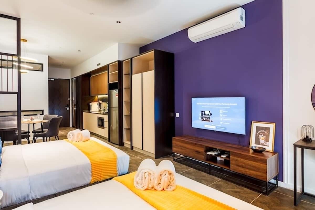 Ein Hotelzimmer mit zwei Betten, einem Essbereich, einem Fernseher und einer Minibar.
