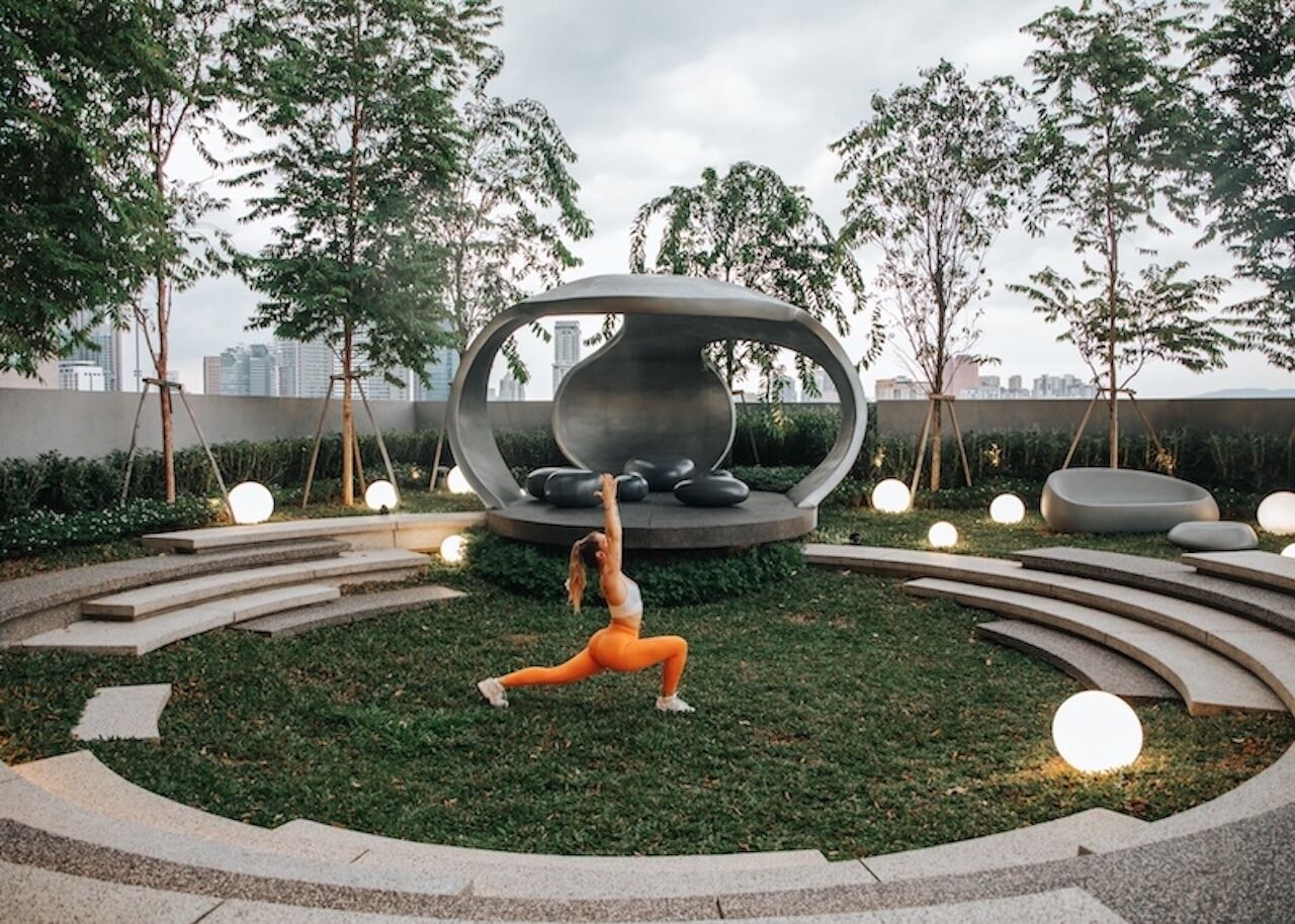 A woman performing a yoga pose in a circular outdoor area with modern seating and lighting.