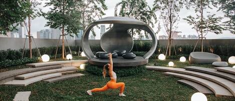 A woman performing a yoga pose in a circular outdoor area with modern seating and lighting.