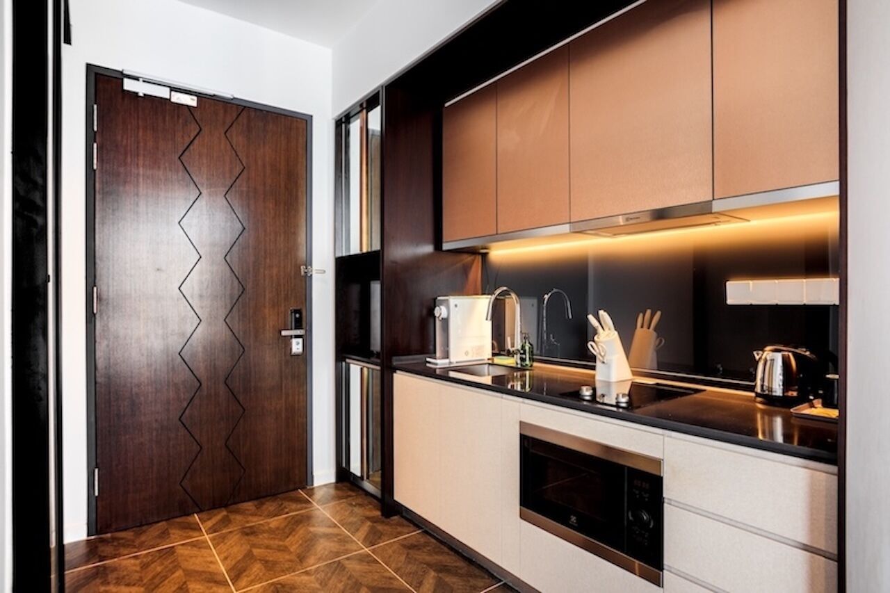A modern kitchen with a wooden door, stainless steel appliances, and a black countertop.