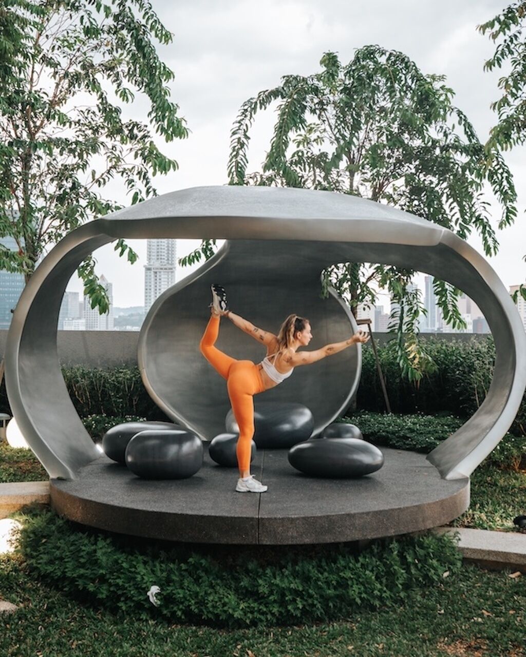 A person performing a yoga pose on a circular platform with a cityscape in the background.