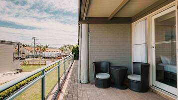 A balcony with wicker chairs, a glass door, and a view of a residential area.