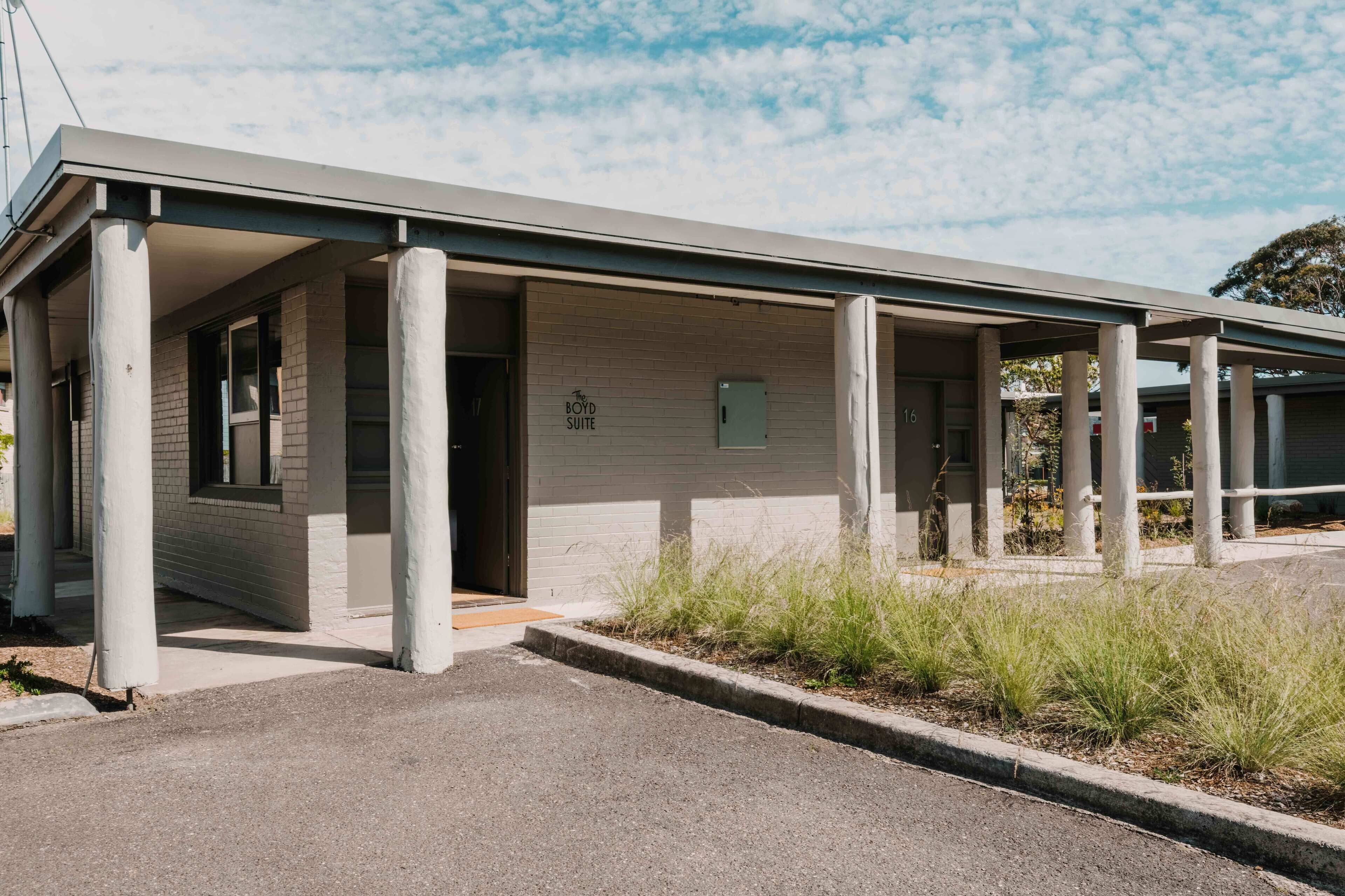 A building with a covered entrance, columns, and a sign indicating 'Boyd Suite'.