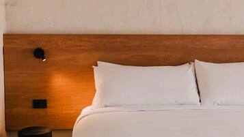 A neatly made bed with white linens and a wooden headboard.