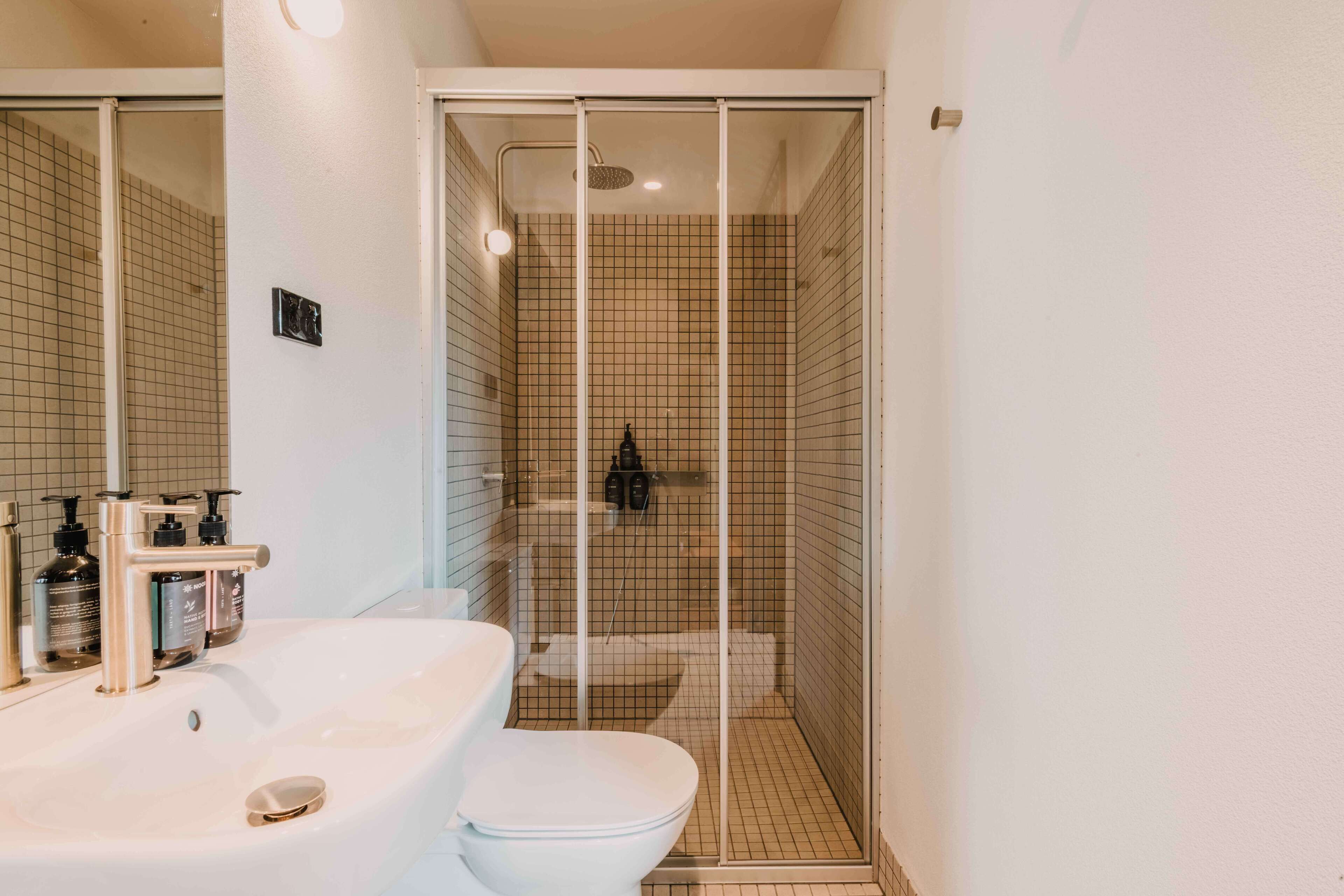 A bathroom with a white sink, toilet, and shower enclosure.