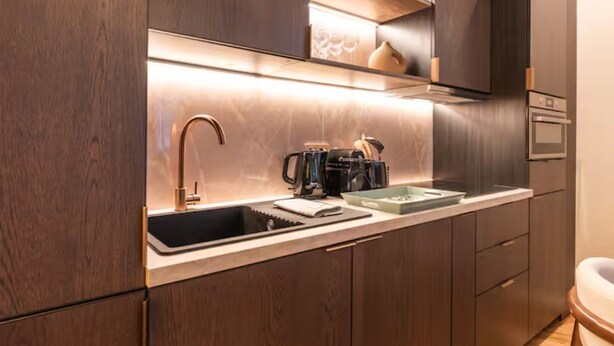 Een moderne keuken met donkere houten kastjes, een roestvrijstalen spoelbak en een inbouwoven.