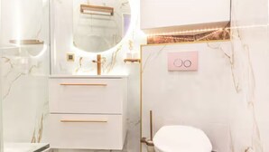 Een moderne badkamer met een marmeren wastafel, toilet en een wandbevestigd wastafelmeubel.