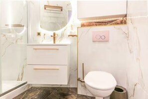 Ein modernes Badezimmer mit Marmorwaschtisch, Toilette und wandmontiertem Waschbecken.