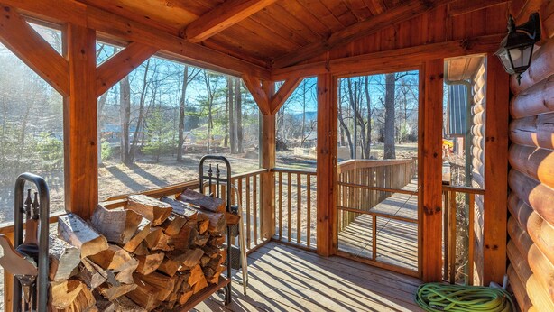 Eine Holzhütte mit Veranda, großen Fenstern und einem Holzstapel.
