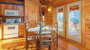 Ein Holzblockhaus-Interieur mit Küche, Essbereich und einem Balkon.