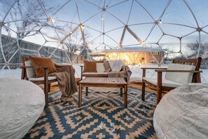 A geodesic dome interior with wooden furniture, a patterned rug, and string lights. - Hot Tub • King Beds • Fast Wi-Fi (Arvada)