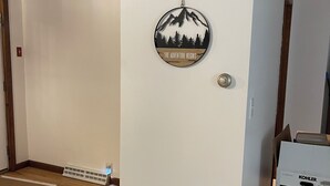 A room with a white wall, a door with a circular decoration, and a box on the floor. - Cozy 2-bedroom cabin in lovely Acra with cool AC (Acra)