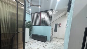 A hallway with a marble floor, a black bench, a potted plant, a staircase, and a ceiling fan. - Urban Hive By T And M Hotels (Haridwar)